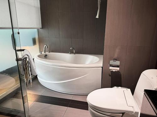 a bathroom with a white tub and a toilet at Golden Tulip Mandison Suites in Bangkok