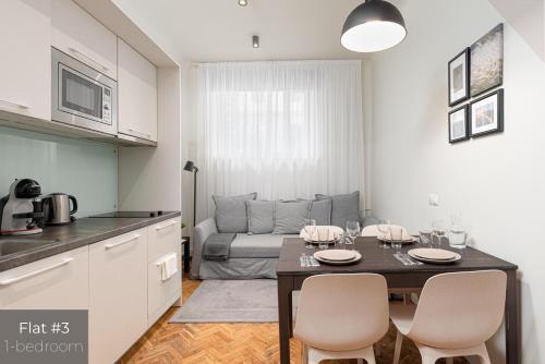 een keuken en woonkamer met een tafel en een bank bij Dandelion Apartments Stabu in Rīga