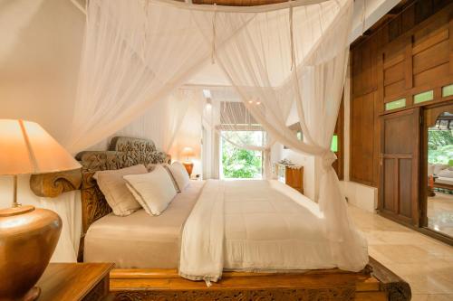 a bedroom with a bed with curtains and a window at The Lavana Ziza Living And Villas Seminyak in Kerobokan