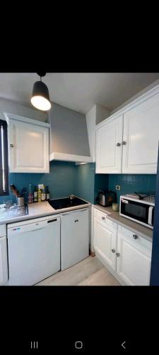 une cuisine avec des armoires blanches et un four à plaques de cuisson dans l'établissement Appartement à côté de la plage, à La Rochelle