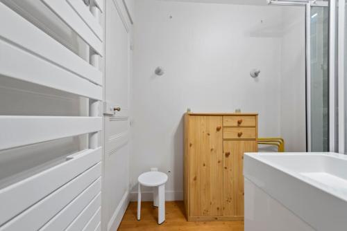 La salle de bains blanche est pourvue d'un lavabo et d'une armoire en bois. dans l'établissement La Maison de Roselyne 5 Pers 250M du centre ville, à Trouville-sur-Mer