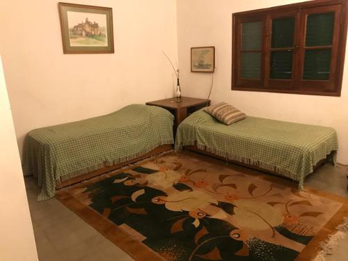 a room with two beds and a table and a rug at Casa de campo La Brea in San Fernando del Valle de Catamarca