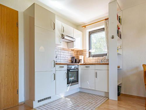 una pequeña cocina con armarios blancos y una ventana en Pühler - Ferienwohnung Möwe en Kronsgaard