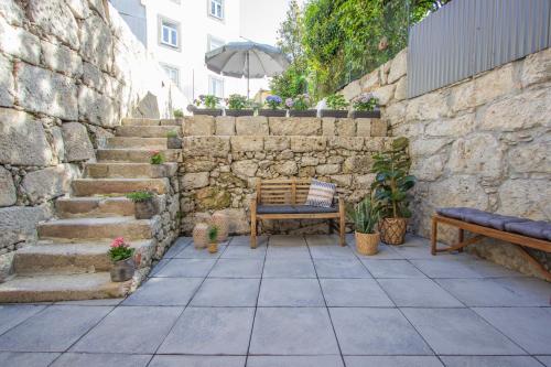 un patio con banco y pared de piedra en Formosa79 Apartments by Guestify en Oporto