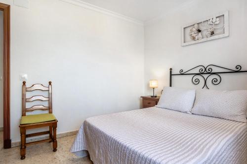 a white bedroom with a bed and a chair at Casa Pinto in Vejer de la Frontera