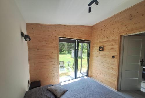 1 dormitorio con paredes revestidas de madera y ventana en W dolinie Rocha en Krasnobród