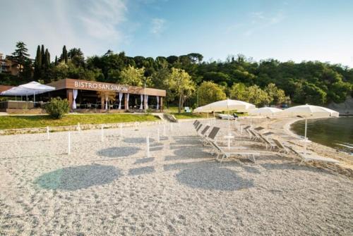 a beach with chairs and umbrellas in front of a building at Rosemary apartment in Izola
