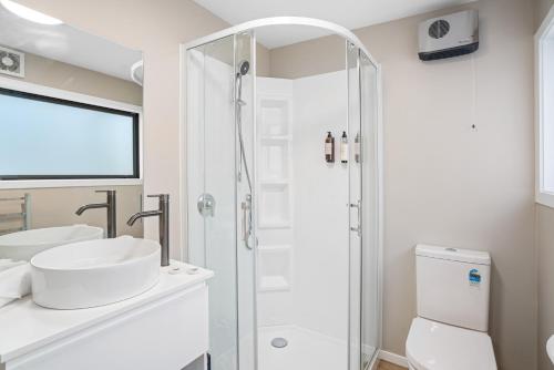 a white bathroom with a shower and a sink at Central Location - 2 Bedroom Aptmt with Lake View in Queenstown