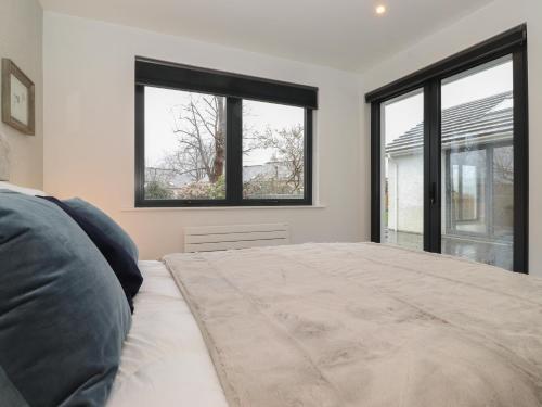 a bedroom with a large bed and two windows at Yonder Lea in Windermere