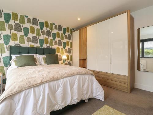 a bedroom with a large bed and a mirror at Yonder Lea in Windermere