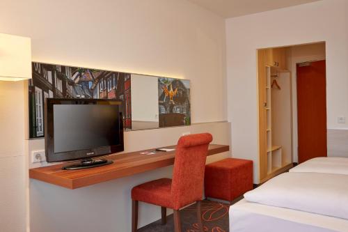 a hotel room with a tv and a bed at H+ Hotel Goslar in Goslar