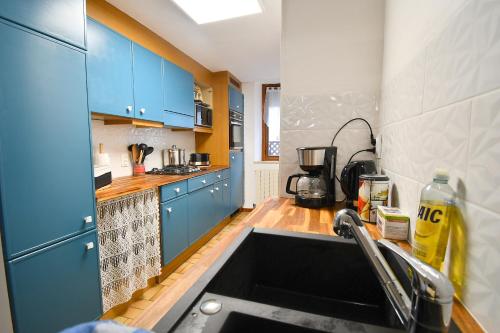 une cuisine avec des armoires bleues et un évier dans l'établissement Le gîte des copains, à Blénod-lès-Toul