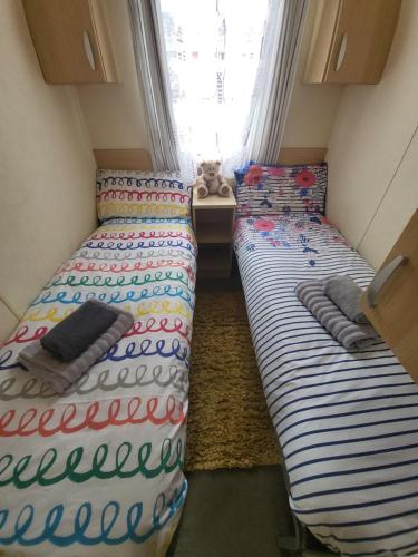 2 camas en una habitación pequeña con un osito de peluche en Caravan on the Devon\Cornwall border, en Stratton