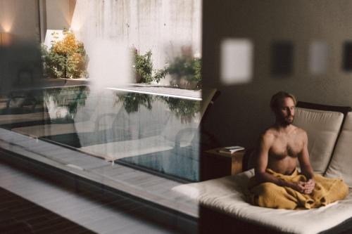 a man sitting in a bed next to a swimming pool at Après Post Hotel in Stuben am Arlberg