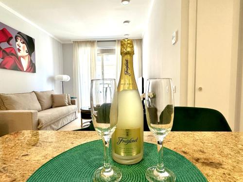 a bottle of champagne and two wine glasses on a table at Reinapart Patacona Beachfront Seaview in Valencia
