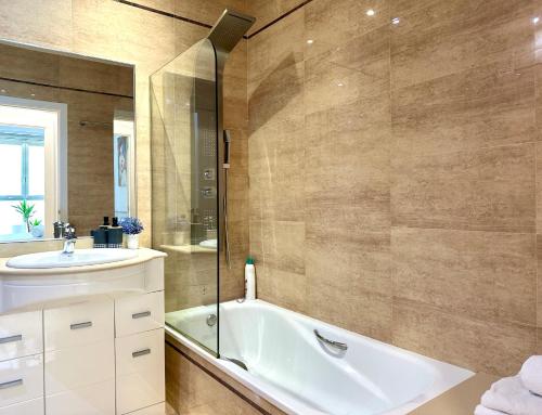 a bathroom with a bath tub and a sink at Reinapart Patacona Beachfront Seaview in Valencia