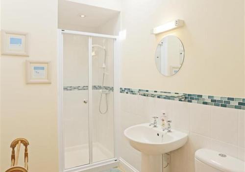 a white bathroom with a shower and a sink at The Cartshed in Wangford