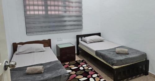 a bedroom with two twin beds and a rug at Beril Homestay Full Aircond, Free Wifi, Netflix, Water Filter in Paka