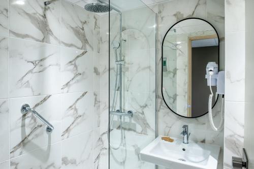 a bathroom with a shower and a sink and a mirror at Hôtel La Solitude in Lourdes