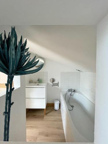 La salle de bains est pourvue d'une baignoire blanche et d'une plante en pot. dans l'établissement Le Guiton - Maison avec terrasse, à La Rochelle