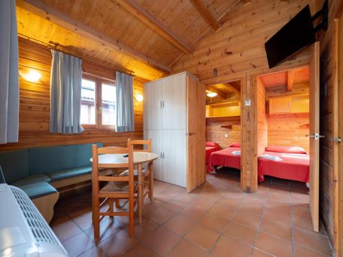una habitación con 2 camas y una mesa en una cabaña en Centro de Vacaciones Morillo de Tou - Ainsa, en Aínsa