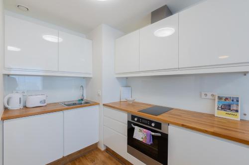 a kitchen with white cabinets and a black oven at Aida City Center Apartment in Pärnu