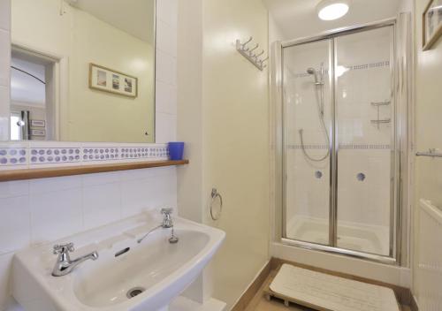 un bagno bianco con doccia e lavandino di The Cottage a Frostenden