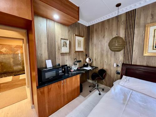 a bedroom with a bed and a desk with a television at Forty 4 On Hoog in Polokwane