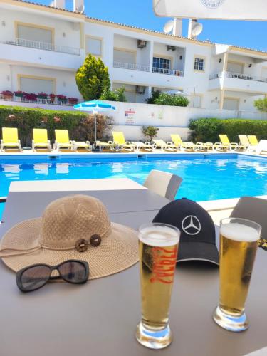 een hoed en bril op een tafel naast een zwembad bij Superior Apartment Casa Vela Albufeira S Rafael beach in Albufeira