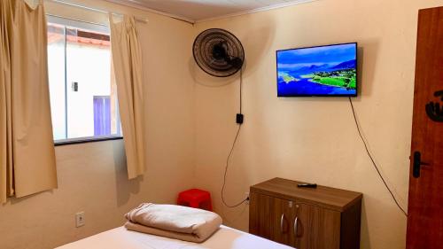um quarto com uma televisão na parede e uma cama em Casa Pitanga - Abraão - IG em Abraão