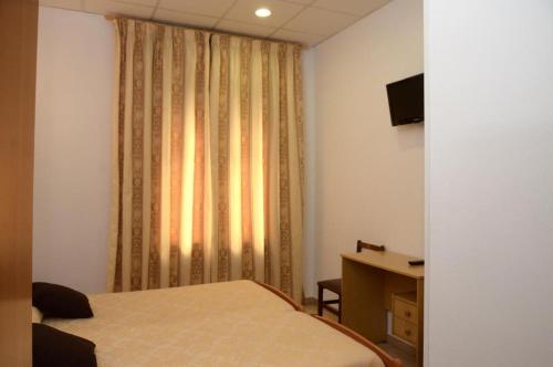 a bedroom with a bed and a desk and a window at Pension Canadiense in Barcelona