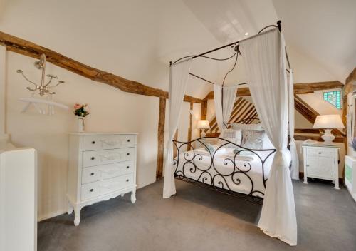 a bedroom with a canopy bed and a dresser at Lady Cottage in Lavenham