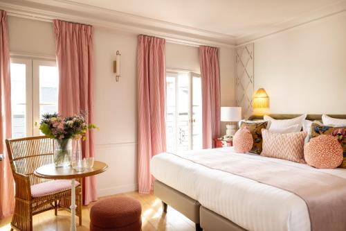 - une chambre avec un grand lit et des rideaux roses dans l'établissement Hôtel Le Lavoisier, à Paris