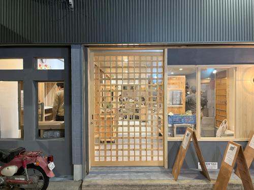a store front with wooden doors and a man working at ゲストハウス 一番街ジャンクション in Fujiidera