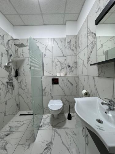 Baño blanco con lavabo y aseo en Hotel Daly, en Ploieşti