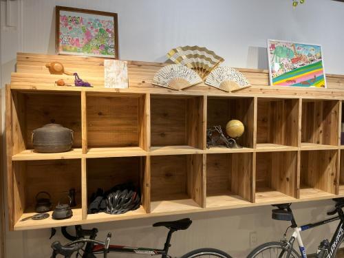 a wooden book shelf with books and a bike at ゲストハウス 一番街ジャンクション in Fujiidera