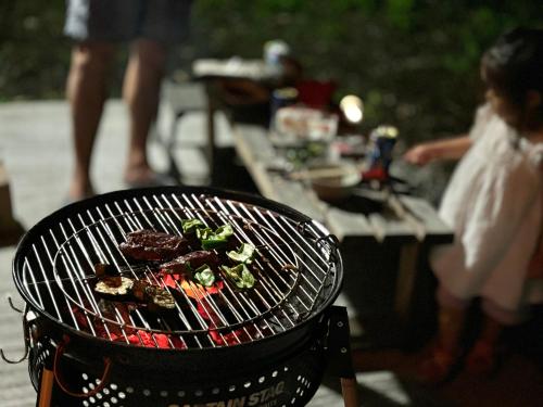 a grill with food on top of it next to a table at まるしっぽ邸-Marushippotei-連泊20パーセントOFF!Onsen,BBQ,hammock,national park,home theater in Murautsuri