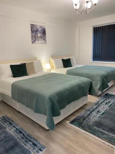 a bedroom with two beds with green sheets and a chandelier at PRIVATE ROOM IN SIDMOUTH STREET, KINGS CROSS in London