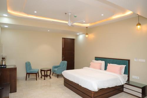 a bedroom with a bed and two blue chairs at HOTEL ROYAL VILAS9 in Gajraula