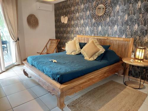 Bett mit blauer Bettwäsche und Kissen in einem Zimmer in der Unterkunft La Villa Zen in Saint-Paul