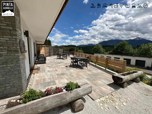 a patio with a table and chairs and mountains at Pinta Kombilo Apartments in Gröbming