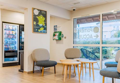 a waiting room with chairs and tables and a refrigerator at B&B HOTEL Poitiers 3 Futuroscope in Chasseneuil-du-Poitou