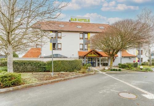 a building with a sign on top of it on a street at B&B HOTEL Poitiers 3 Futuroscope in Chasseneuil-du-Poitou