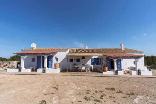 una casa blanca con mesas y sillas frente a ella en Cas Saliners - Villa Can Paya, en La Savina