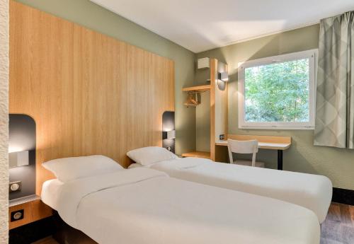 2 letti in una camera con scrivania e finestra di B&B HOTEL Béziers a Béziers