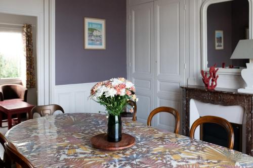 une table de salle à manger avec un vase de fleurs dessus dans l'établissement Villa Zachee - maison familiale & parking gratuit, au Tréport