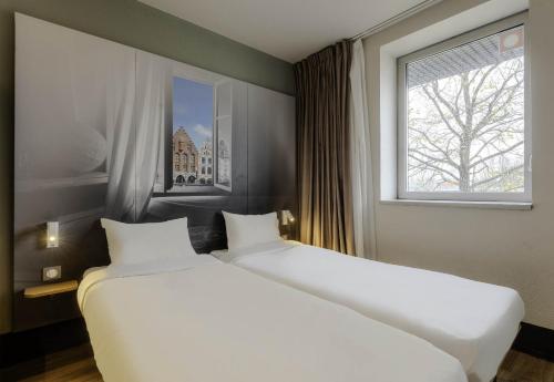 2 camas blancas en una habitación con ventana en B&B HOTEL Arras en Arras