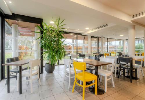 ein Restaurant mit Tischen und Stühlen und einer Topfpflanze in der Unterkunft B&B HOTEL Arras in Arras