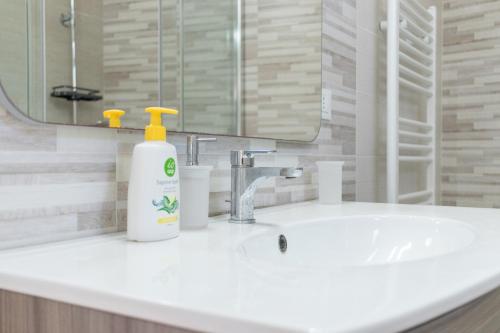 a bathroom sink with a bottle of soap and a mirror at Dimora Dorè in Marittima