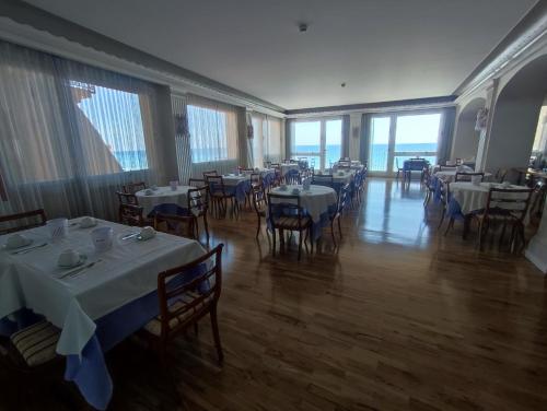 a dining room with tables and chairs and windows at Hotel Tirreno in Alassio